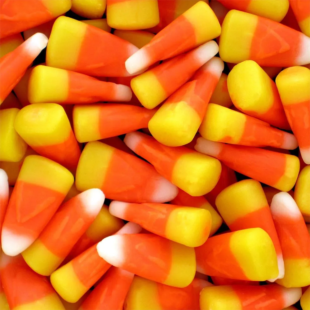 A close-up pile of classic candy corn, each piece in three layers of yellow, orange and white